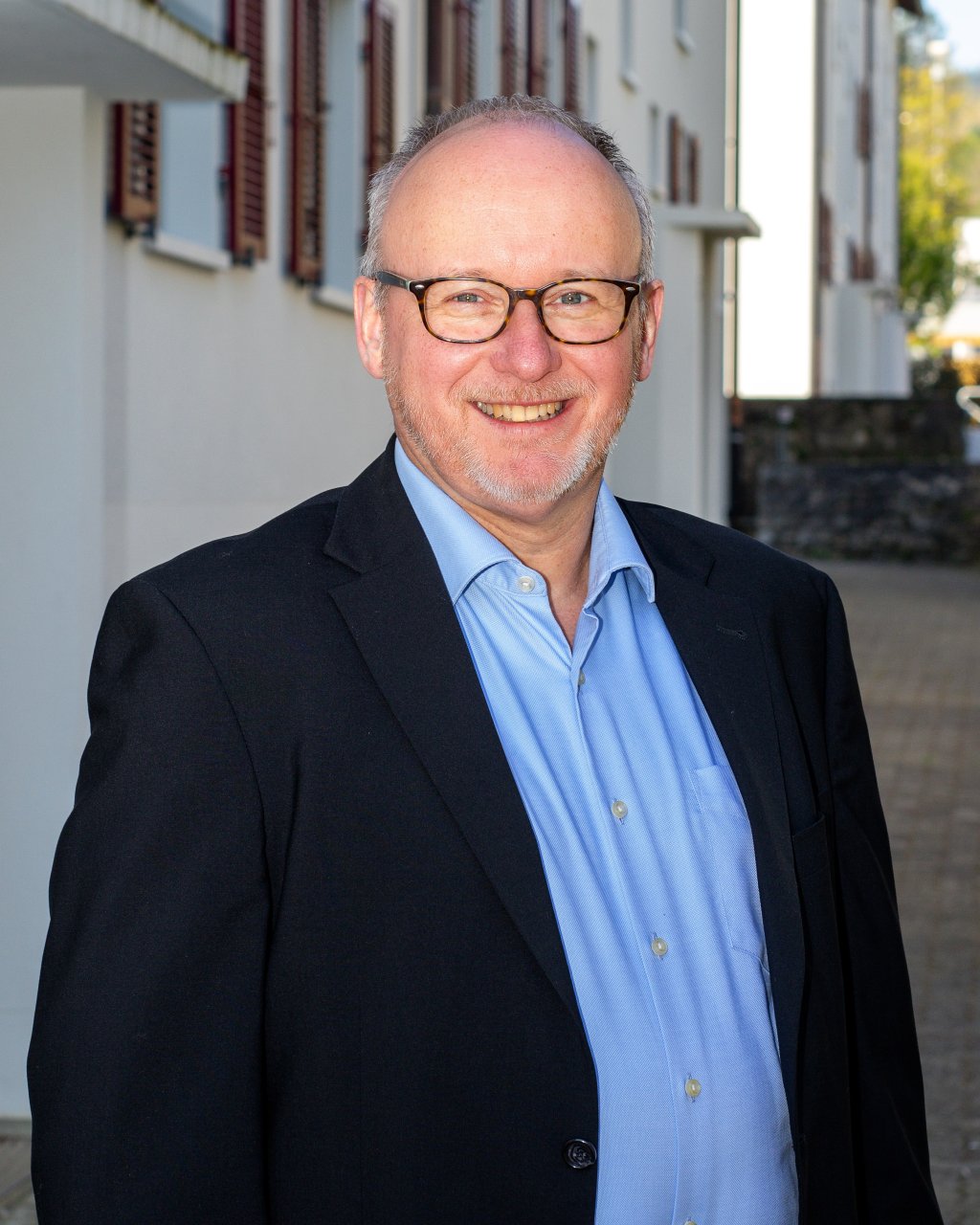 Bild des Kassiers, Christian Ballmer, trägt Brille, Hemd und Blazer, lächelnd