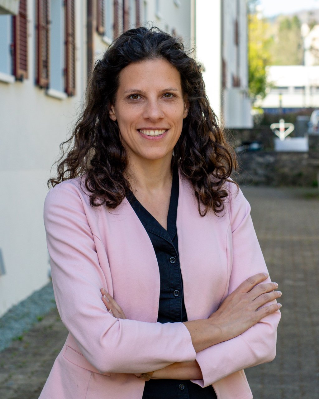 Bild der Aktuarin, Justine Muya, rosa Blazer, dunkle lockige Haare